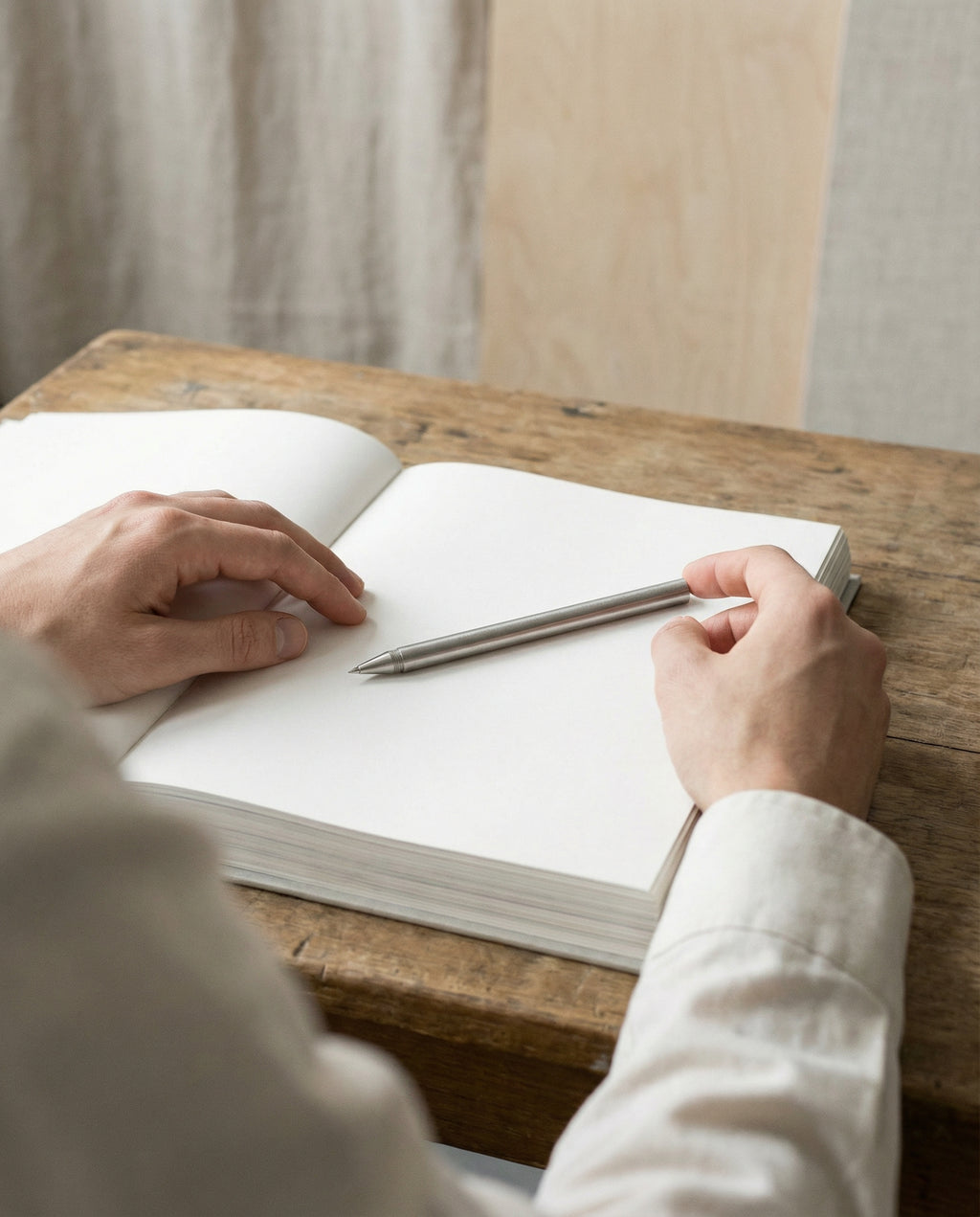 Design kuglepen i stål placeret på åben notesbog på skrivebord.