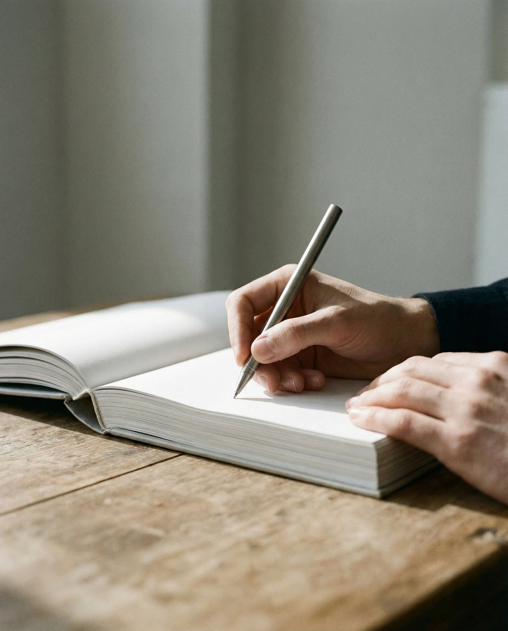 Person skriver i hånden i notesbog med design kuglepen i stål.