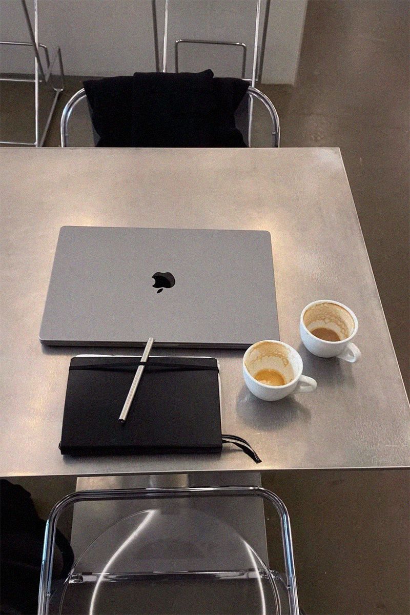 The Pen ligger på en sort notesbog ved siden af en MacBook og to kaffekopper – et minimalistisk arbejdsrum i nordisk design.